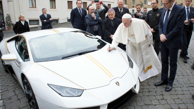 Pope Francis writes on the bonnet of a Lamborghini donated to him by the luxury sports car maker,.