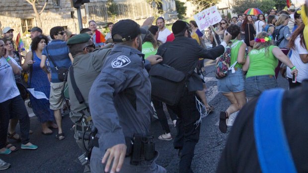Security forces reach for a knife-wielding ultra-Orthodox Jewish man at a Gay Pride march in Jerusalem.