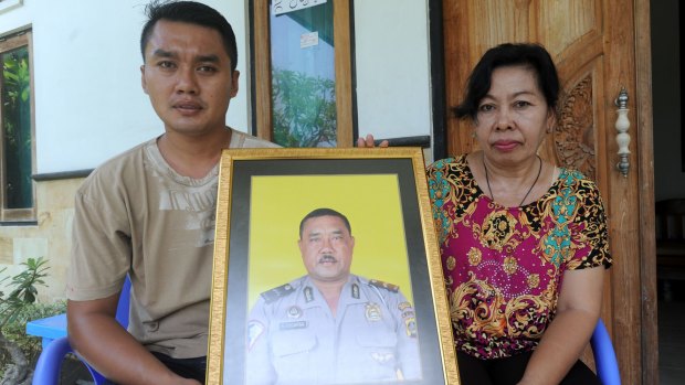 The widow of Wayan Sudarsa, Ketut Arsini, and her son Kadek Toni, hold a portrait of the police officer who was killed on Legian beach. 