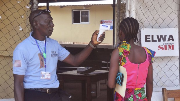 A family member of a boy who contracted Ebola has her temperature taken by a health worker at an Ebola clinic on the outskirts of Monrovia, Liberia.