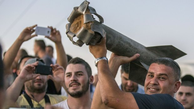 Israelis, mostly from the southern Israeli city of Sderot, show the remains of a rocket on July 13, 2014. 