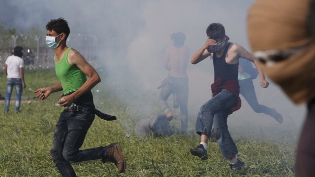 Migrants run from tear gas during protests at a border control fence on the Macedonian-Greek border on Sunday. 