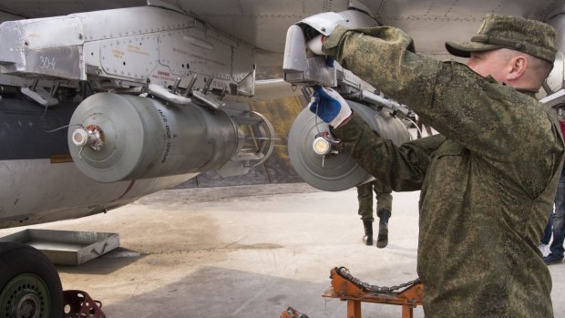 A Russian air force technician attaches a bomb to a Russian ground attack jet at an air base in Syria.