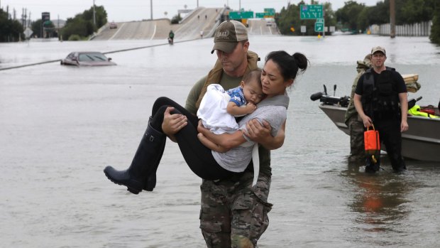 Houston Police SWAT officer Daryl Hudeck carries Connie Pham and her 13-month-old son Aiden after rescuing them from their home.