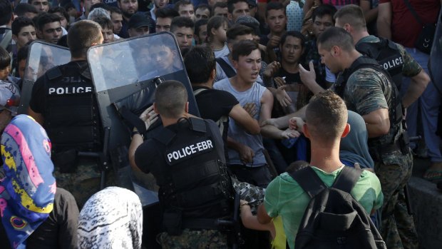 Police officers confront migrants at the railway station in Gevgelija.  