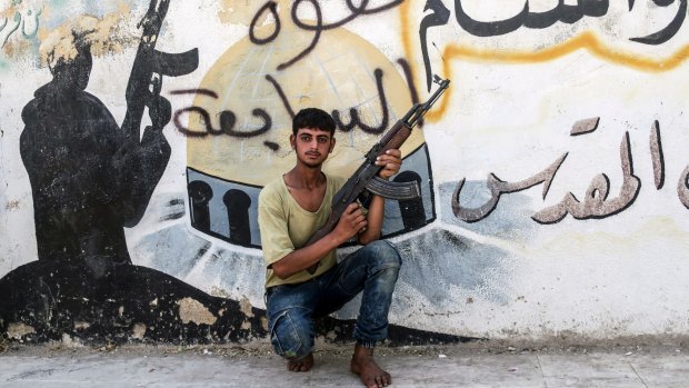 A Free Syrian Army fighter poses   in front of a mural left by Islamic State militants in Jarablus after its liberation.