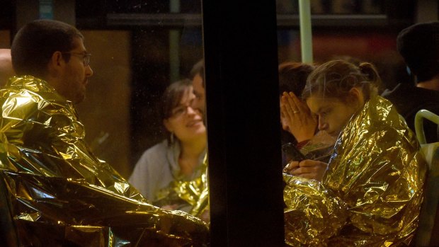 Survivors of the concert hall shooting huddle on a bus. 
