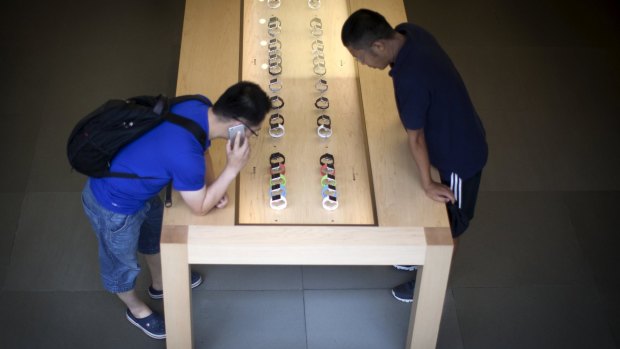Customers look at Apple Watches inside the Apple store on 5th Avenue in New York City.