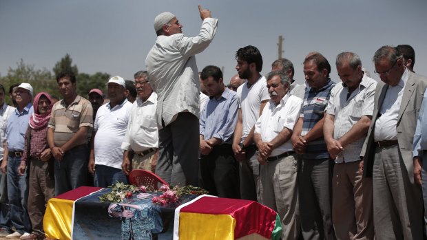 Mourners pray by the coffin of Kurdish fighter Mehmet Resat Cinar, killed in the fighting for Tal Abyad.
