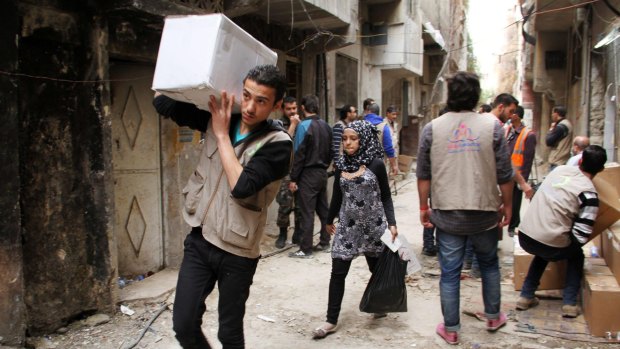 UNRWA staff members distribute aid to residents of the Yarmouk Palestinian refugee camp near Damascus in March 2015. 