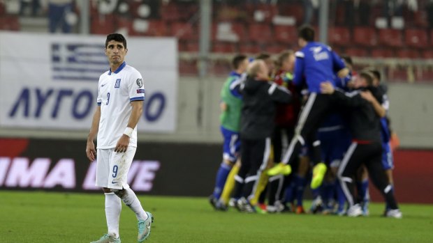 Greece's Petros Mantalos leaves the pitch as Faroe Islands' players celebrate.