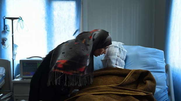 Sana Abdul Amir listens to her son Abdulrahman Abdulaaly, who has burns to 60 per cent of his body.