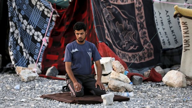 A Syrian refugee from Tel Abyad prays in front of his makeshift tent in Akcakale, in Turkey's Sanliurfa province.