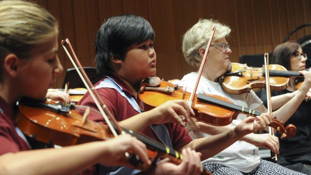 Goulburn Public School year five pupils Teesha Jones, left, and Brendell Guiao sit next to CSO first violinist Barbara Jane Gilby at a rehearsal for Tuesday's performance.
