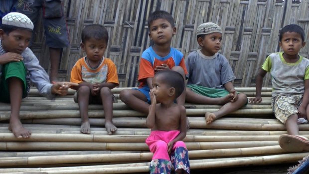 Rosmaida Bibi, foreground, sits on a pile of bamboo trees with other children of her age at the Dar Paing camp.