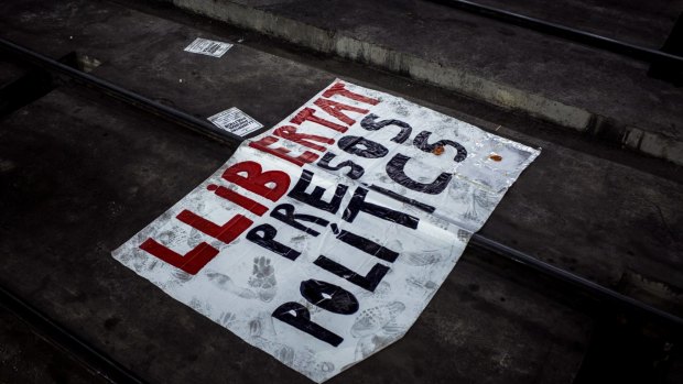 A banner demanding 'Freedom for political prisoners' lies on the rail tracks as protesters occupy Barcelona Sants central station.
