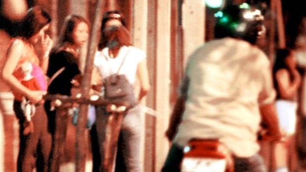 A motorcyclist rides past a group of young women hanging out near the Lumpini park in Bangkok.