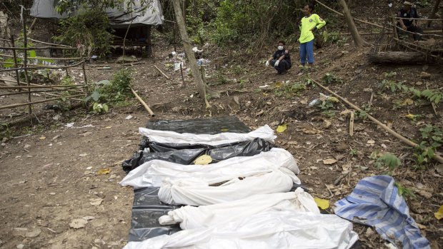Rescue workers rest behind body bags with human remains retrieved from a mass grave near the border with Malaysia, in Thailand's southern Songkhla, province in May.