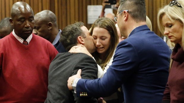 Oscar Pistorius, centre left, hugs his sister Aimee, centre right, as he leaves the High Court after sentencing.