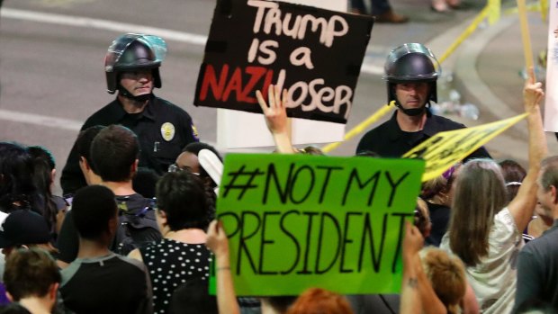 People protest outside the Phoenix Convention Centre on Tuesday evening, while US President Donald Trump delivers a campaign-style speech inside.
