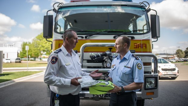 ACT Rural fire service Chief Officer Joe Murphy SES senior manager Operations and governance Rob Thompson inspect the automatic external defibrillator. 