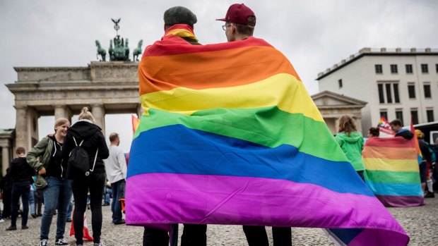 Men with rainbow flags stand in front of the Brandenburg Gate to celebrate the legalisation of same-sex marriage in Germany.