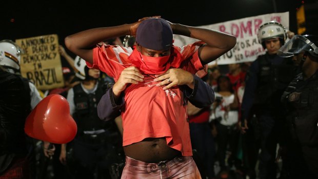 An anti-impeachment demonstrator is frisked after clashes with police outside the National Congress building while the Senate vote is held.