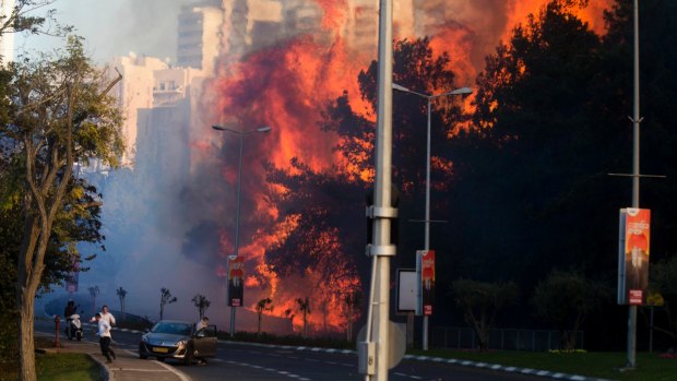 People run as fires rage in Haifa, Israel, on Thursday.