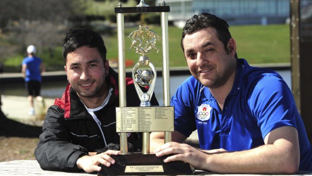 Canberra FC captain Aidan Brunskill and Canberra Olympic skipper Angelo Konstantinou with the trophy they will be playing for in Sunday's ACT NPL grand final.