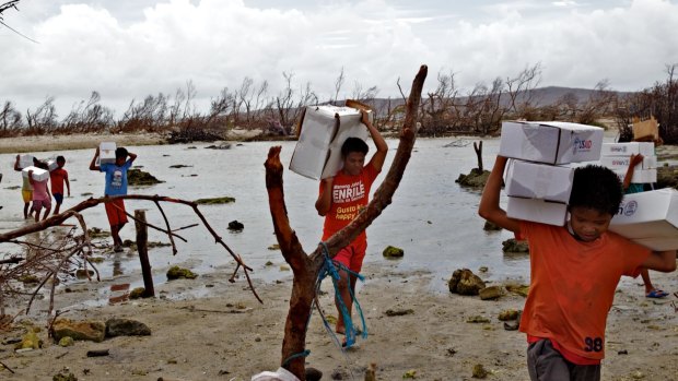 Locals carry aid packages after Cyclone Haiyan hit the Philippines.