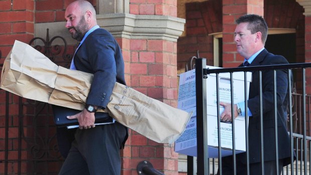 Detective Senior Constable John Cosgrove and Detective Sergeant Darren Gunn carry evidence into the Wagga courthouse, including what is believed to have been a shotgun involved in the deaths of the Hunt family. 