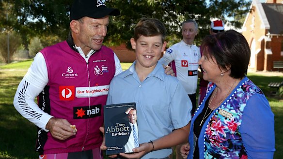 Tony Abbott hands out a copy of his book Battlelines during his Pollie Pedal fundraiser. 