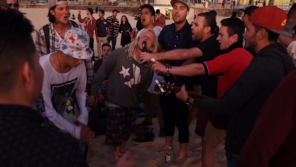 Revellers sing and dance moments before the sun rises over Bondi Beach.