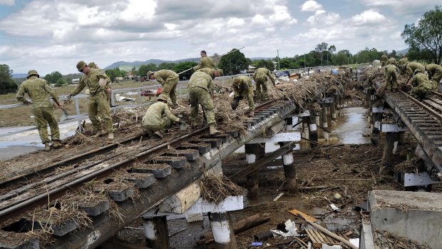 Soldiers from 8th/9th RAR, and engineers from 2nd CER, clear the train line that runs through Grantham, Queensland, after flooding in 2011.