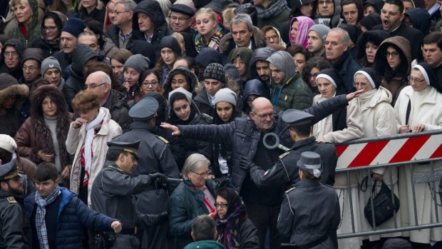 Faithful and pilgrims wait to go through security checks to enter St. Peter's Square for the start of a Mass celebrated by Pope Francis at the Vatican on Tuesday. 