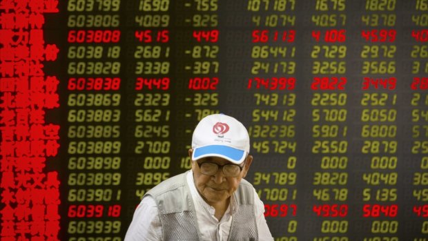 A Chinese investor walks past displays of stock information at a brokerage house in Beijing. 