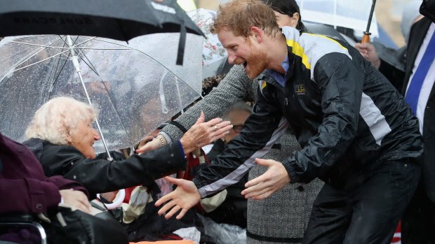 Prince Harry hugs 97-year-old Daphne Dunne during a walkabout in the torrential rain ahead of a Sydney 2018 Invictus Games Launch Event at the Overseas Passenger Terminal.