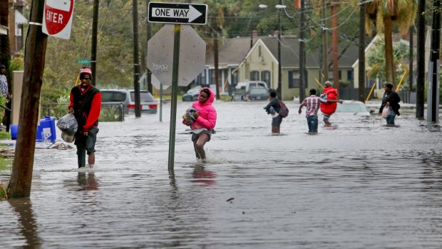 A group of people cross through high water after Hurricane Matthew caused flooding in Charleston, South Carolina.