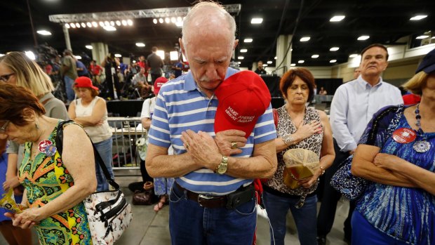 Supporters bow their heads in prayer before Republican presidential candidate Donald Trump delivers a campaign speech in Charlotte, North Carolina.