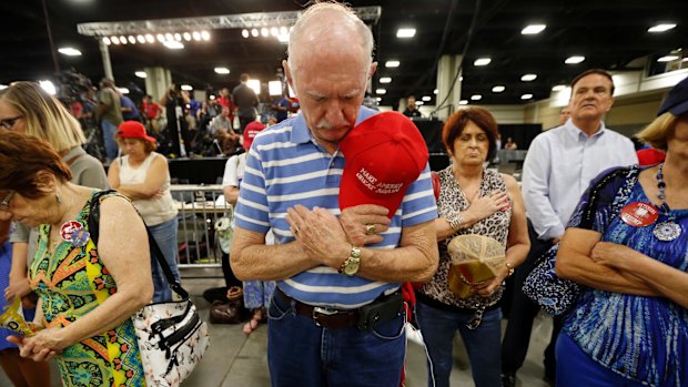 Supporters bow their heads in prayer before Republican presidential candidate Donald Trump delivers a campaign speech in Charlotte, North Carolina.