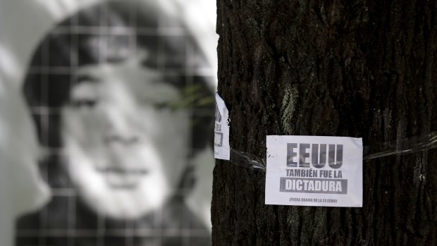 A picture of a person who disappeared during the last military dictatorship is seen behind a leaflet on a tree that reads in Spanish "The US was also the dictatorship, Obama out of former Argentine Navy School of Mechanics".  