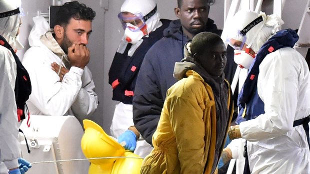 The ship's captain and migrants stand on the deck of the Italian Coast Guard ship Gregretti, believed to be carrying 27 survivors of the migrant shipwreck in the Mediterranean.