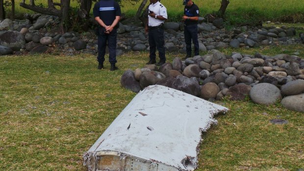 French gendarmes and police stand near a large piece of plane debris which was found on the beach in Saint-Andre, on the French Indian Ocean island of La Reunion.