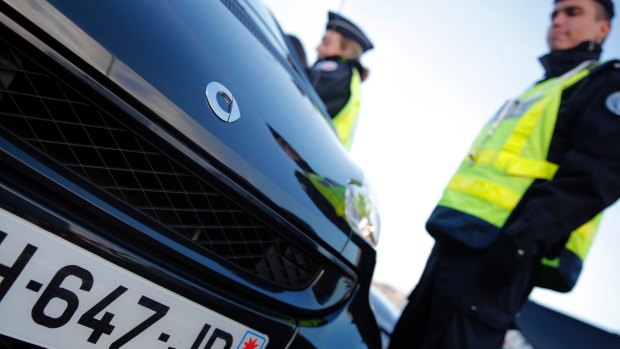 Police officers check cars as Paris suffers a pollution spike.