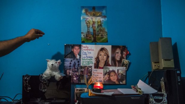 Carlos Saldana reaches to adjust the small shrine created in memory of his and Vicky Delgadillo's missing children, in the bedroom of their home in Xalapa.