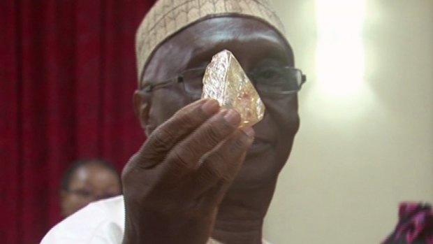 Sierra Leone's Minister of Mines and Mineral Resources Alhaji Minkailu Mansaray hands a diamond during a meeting with delegates of Kono district, where the gem was found.