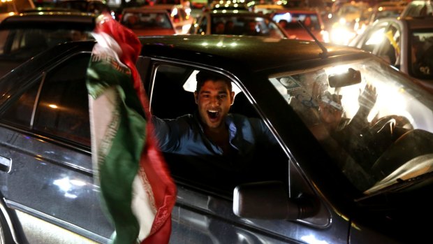 An Iranian waves his country's flag while celebrating on a street in northern Tehran after Iran's nuclear agreement with world powers in Lausanne, Switzerland. 