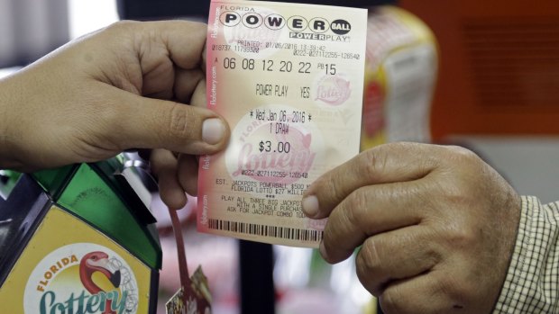 A clerk hands over a Powerball ticket to a customer at a grocery store in Florida.