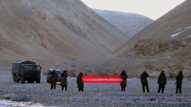 Chinese troops hold a banner reading "You've crossed the border, please go back" in Ladakh, India. 