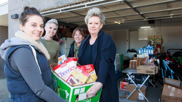 The stock inside Carly Montgomery's garage, (l-r) Carly Montgomery, mill worker's wife Sharran George and Dannie Townsend-O'Neil presenting a food box to mill worker Emily Folan.